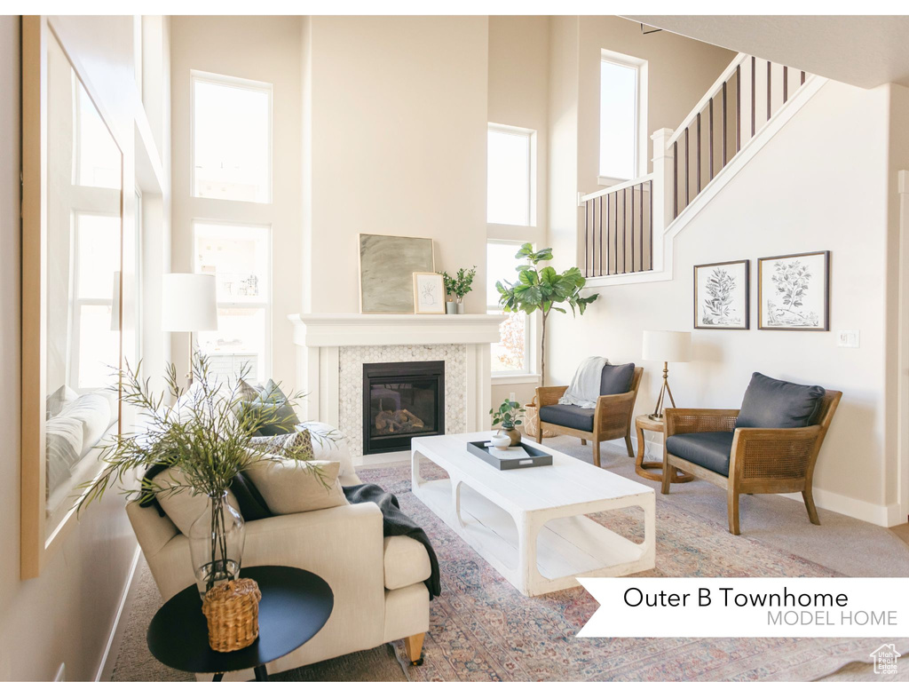 Living area with a wealth of natural light, a high ceiling, and a glass covered fireplace