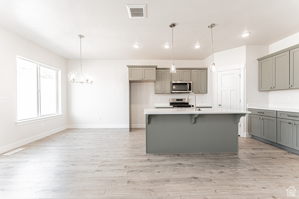 Kitchen with gray cabinets, stainless steel appliances, recessed lighting, and light countertops