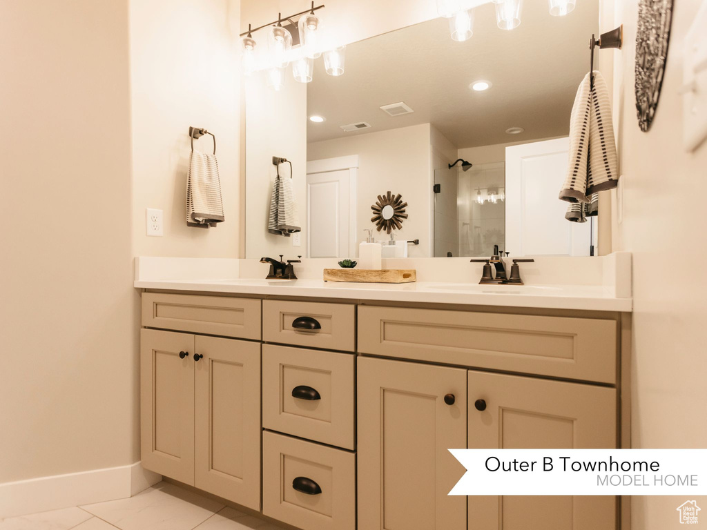 Bathroom with baseboards, visible vents, double vanity, a tile shower, and a sink
