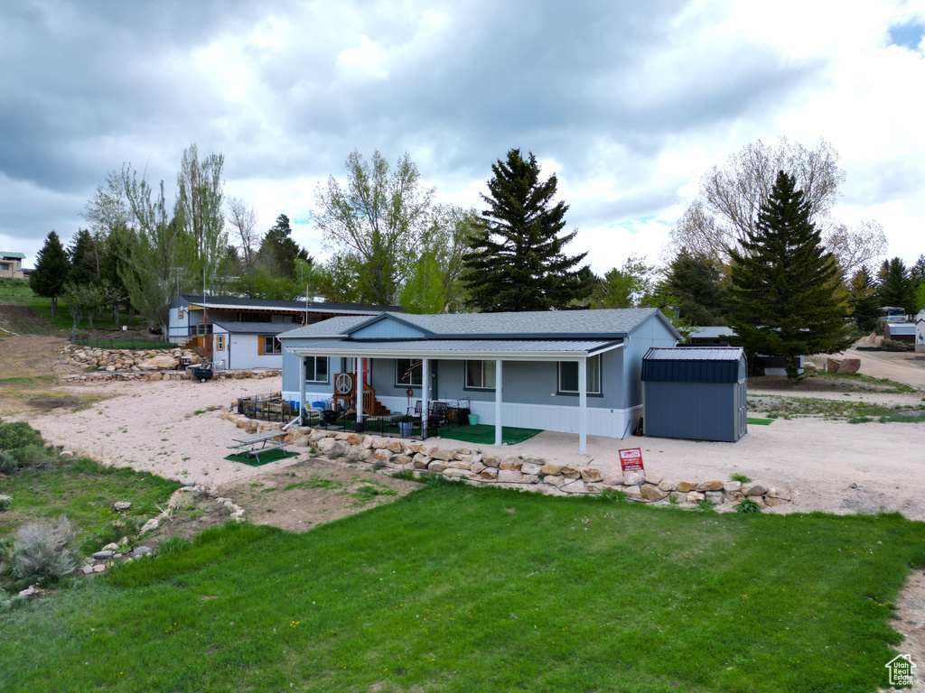 View of front of house with a porch, a front yard, roof with shingles, and an outdoor structure