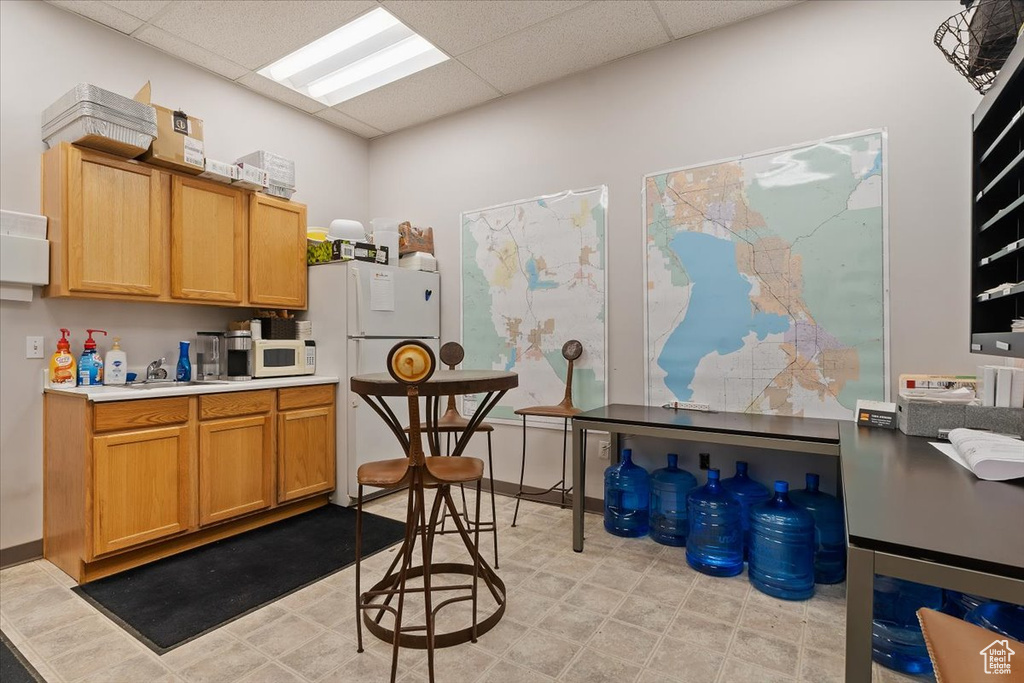 Kitchen with a paneled ceiling, white appliances, and light countertops