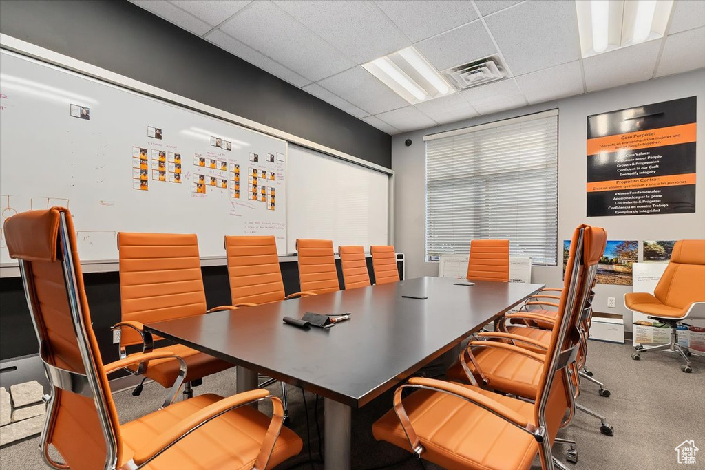 Carpeted office space featuring a drop ceiling and visible vents