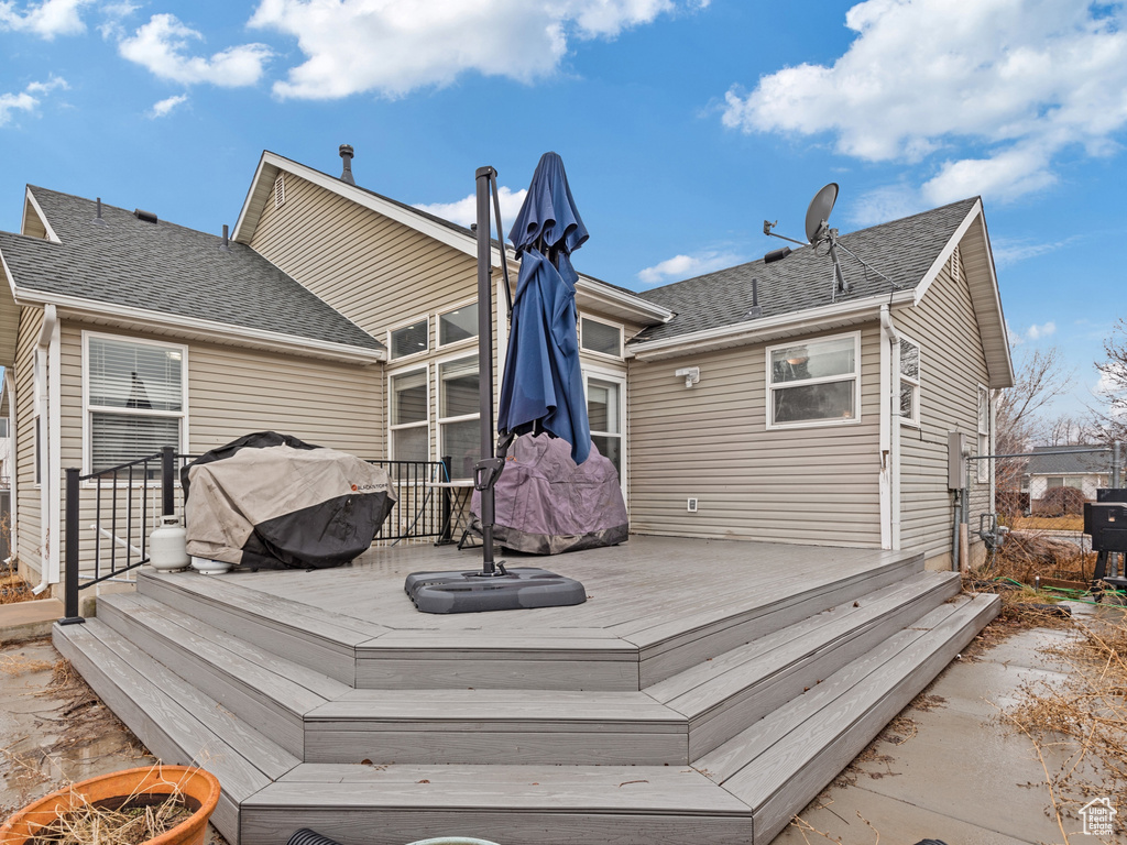 Rear view of property featuring roof with shingles and a wooden deck