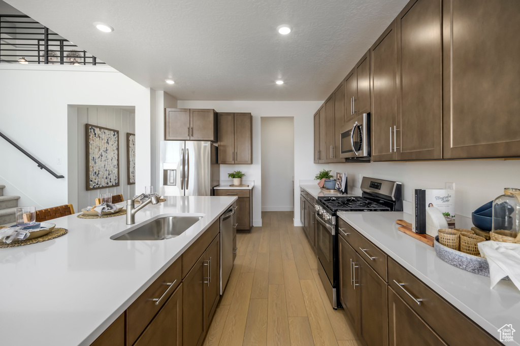 Kitchen featuring light wood finished floors, light countertops, recessed lighting, stainless steel appliances, and a sink