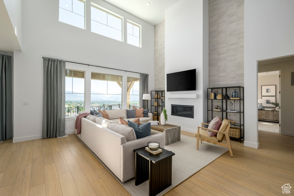 Living area with baseboards, a high ceiling, a fireplace, and light wood finished floors