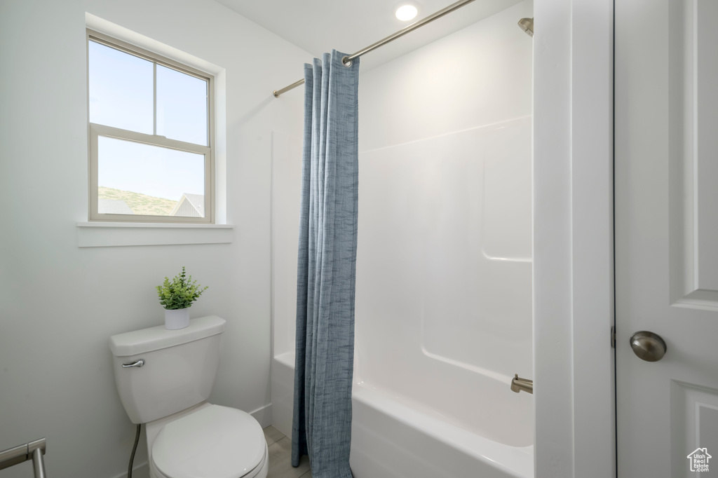 Bathroom featuring shower / bath combination with curtain and toilet
