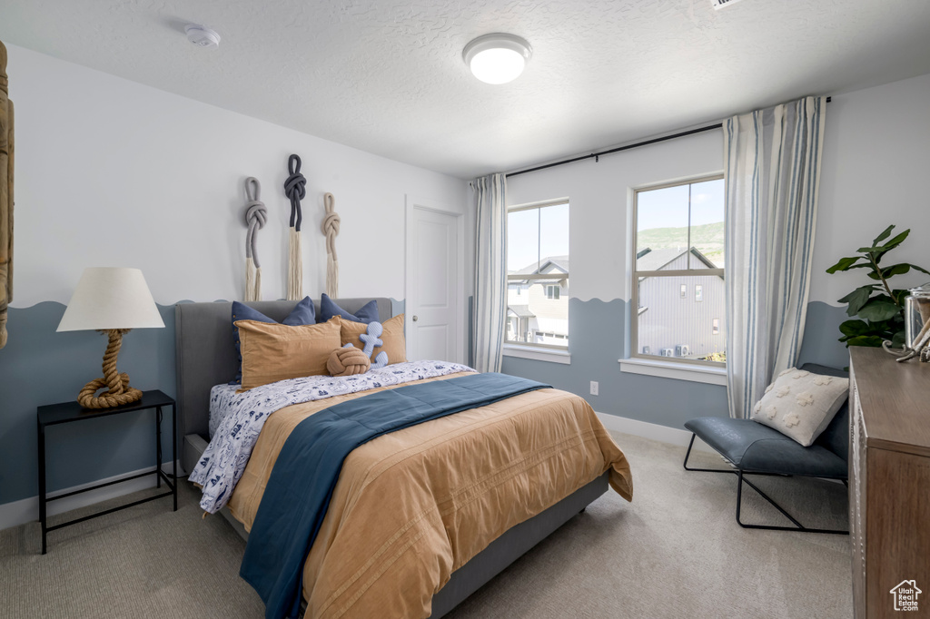 Carpeted bedroom featuring baseboards and a textured ceiling