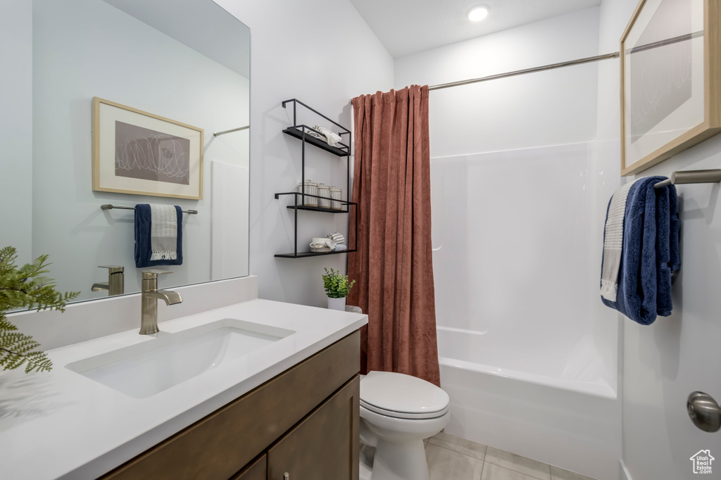 Bathroom featuring tile patterned floors, shower / bath combo with shower curtain, toilet, and vanity