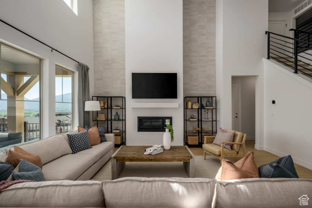Living area featuring wood finished floors, a fireplace, baseboards, a towering ceiling, and stairs