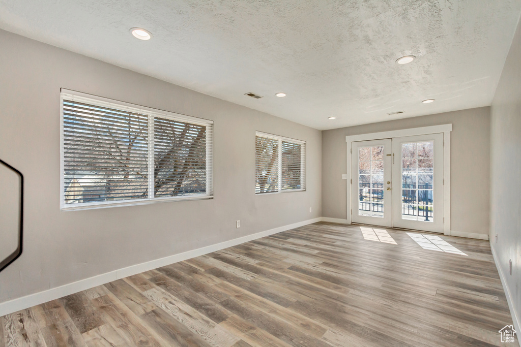 Empty room with visible vents, baseboards, a textured ceiling, and wood finished floors