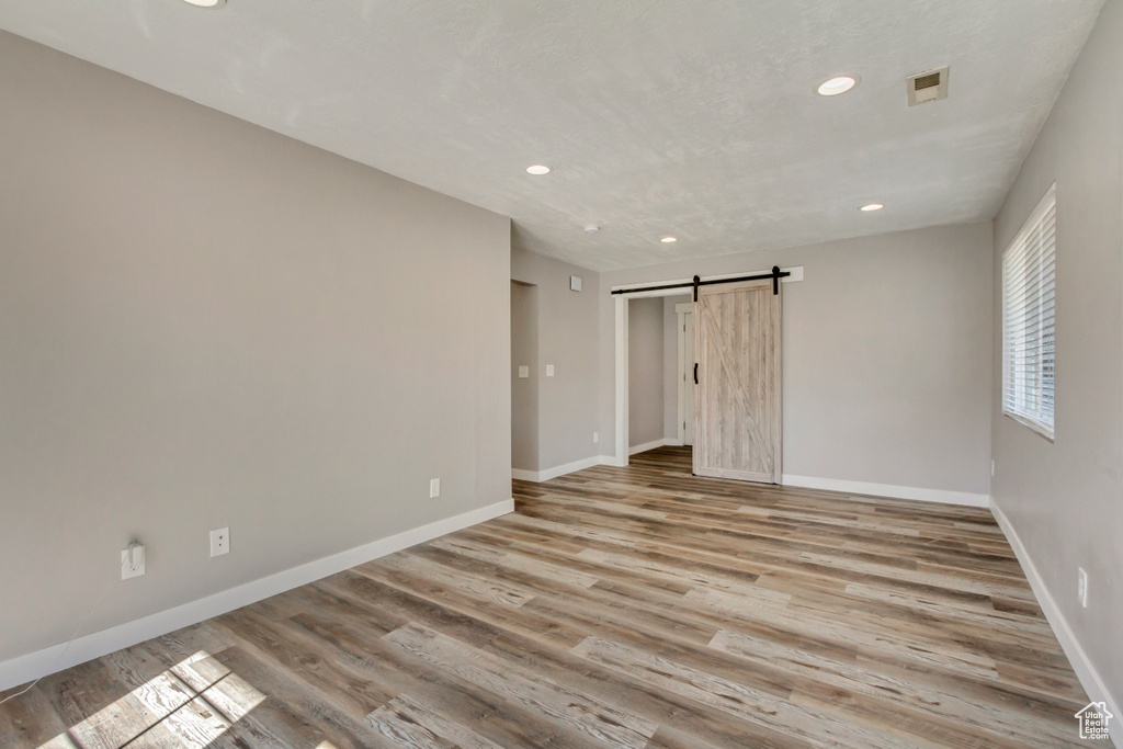 Spare room with baseboards, visible vents, light wood finished floors, recessed lighting, and a barn door