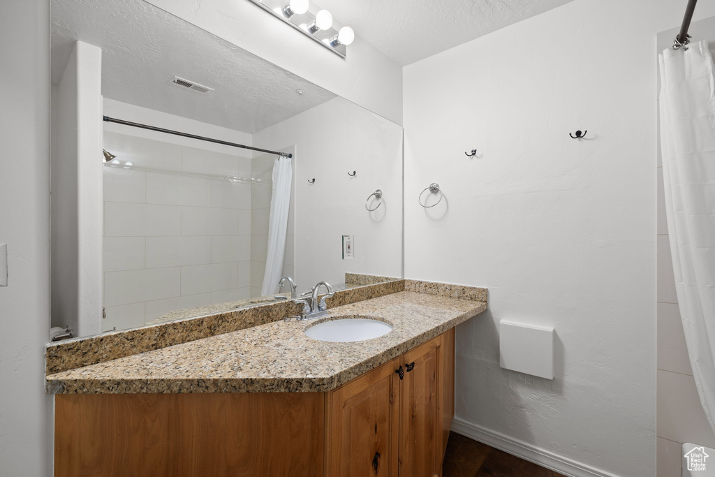 Full bathroom with vanity, curtained shower, and wood finished floors