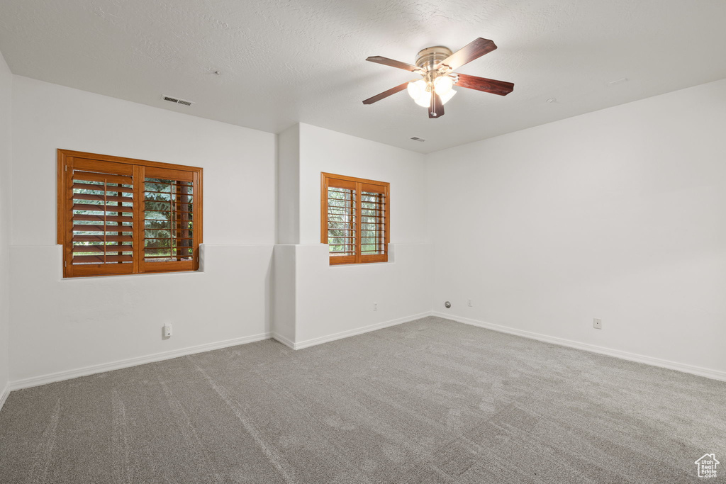 Carpeted empty room with ceiling fan and baseboards