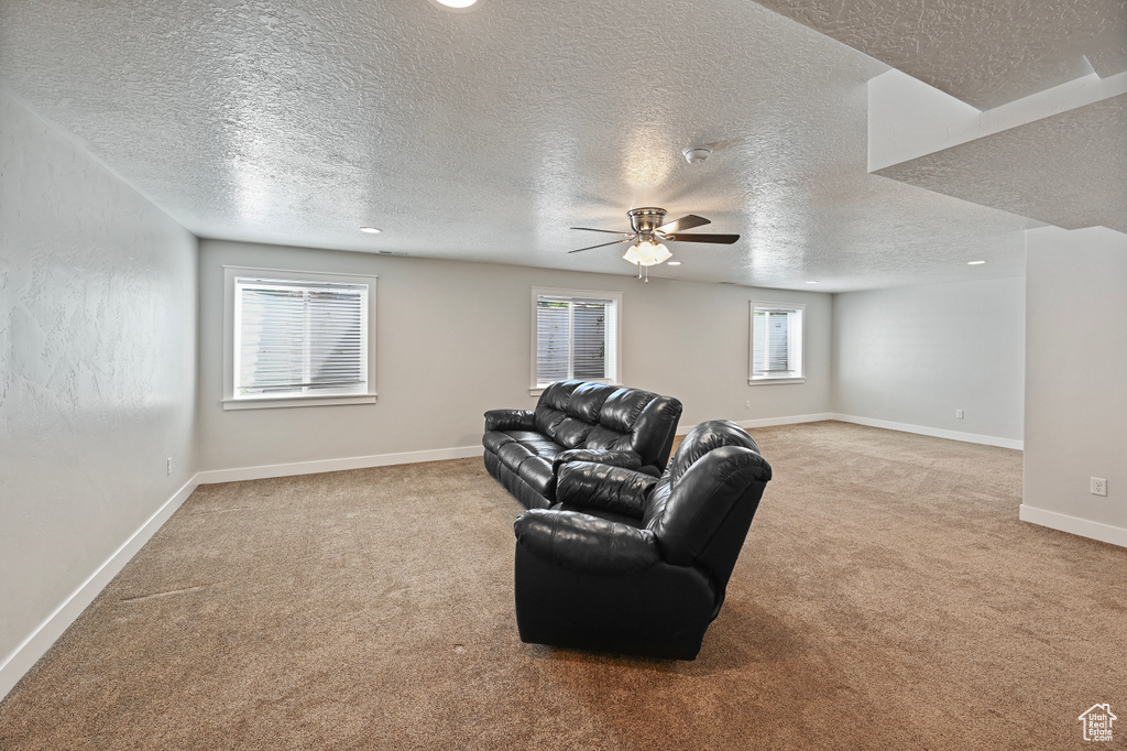 Living room with carpet, a ceiling fan, a textured ceiling, and baseboards