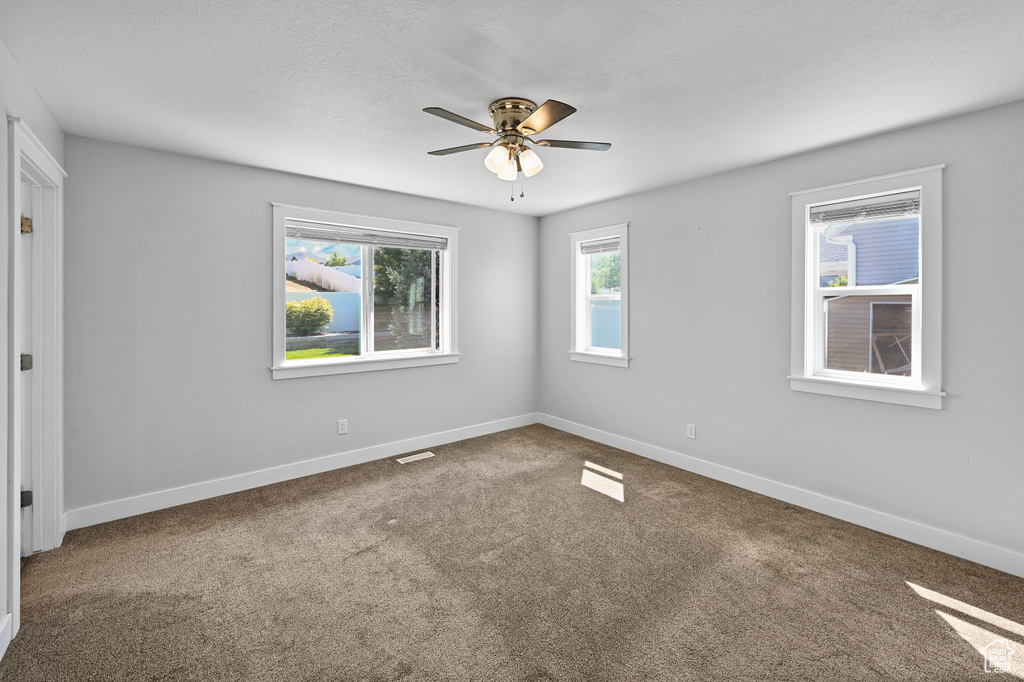 Carpeted spare room featuring a ceiling fan and baseboards