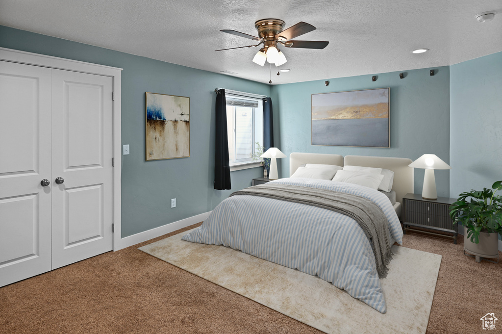 Carpeted bedroom with a textured ceiling, baseboards, a closet, and ceiling fan