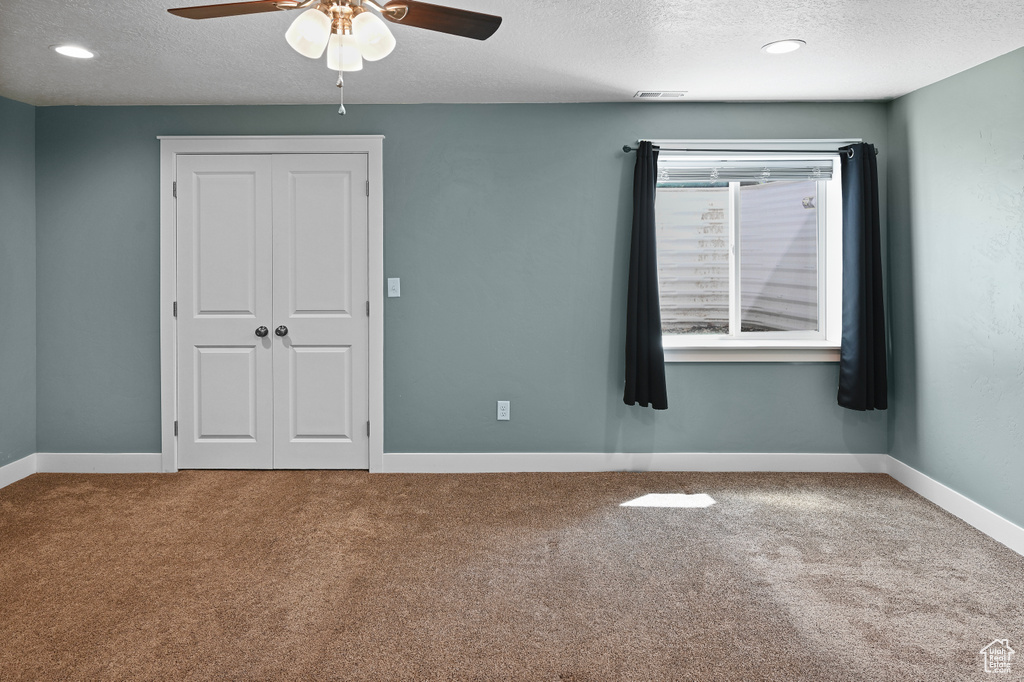 Unfurnished bedroom with a textured ceiling, carpet, a closet, ceiling fan, and baseboards