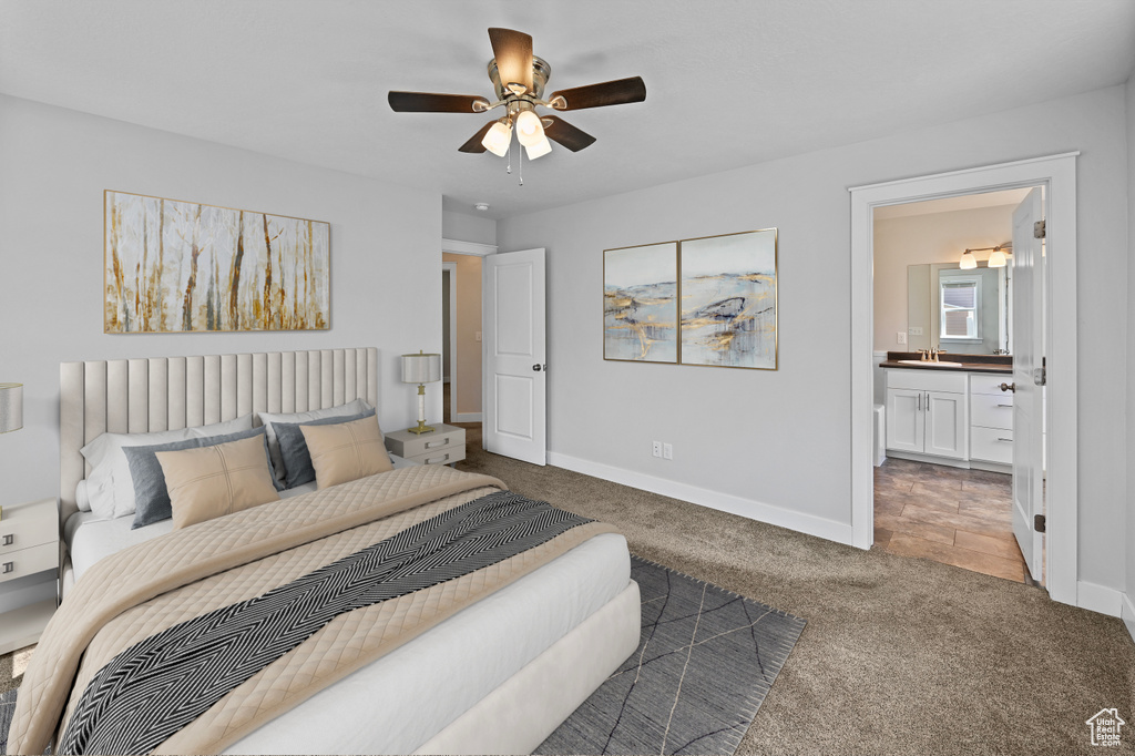 Carpeted bedroom with baseboards, connected bathroom, ceiling fan, and a sink