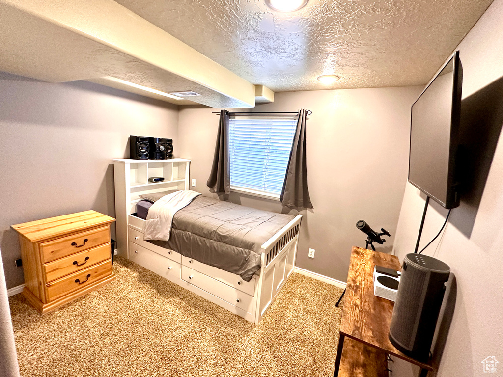 Carpeted bedroom with baseboards and a textured ceiling