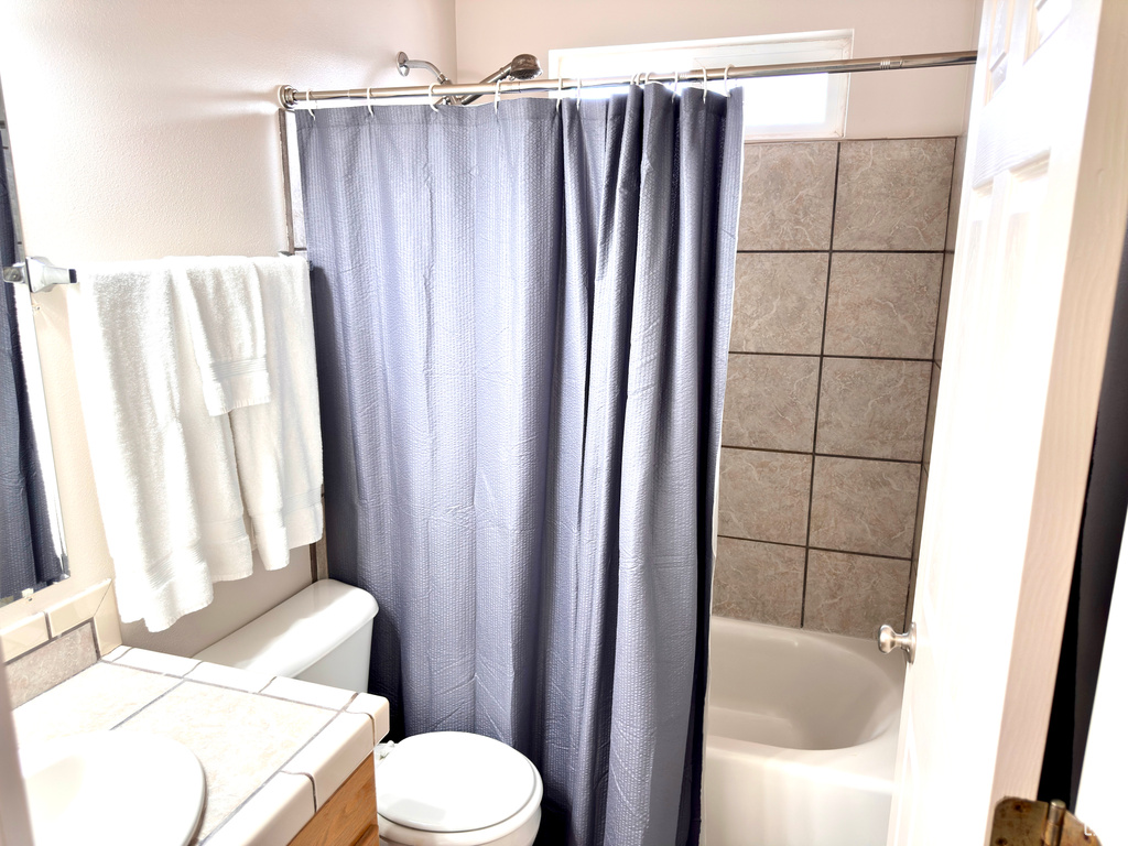 Bathroom featuring toilet, vanity, and shower / bathtub combination with curtain