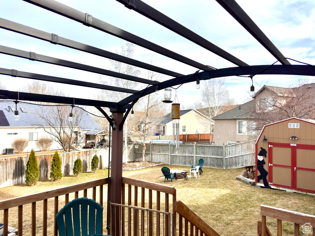 Exterior space with a fire pit, a pergola, a fenced backyard, an outdoor structure, and a storage unit