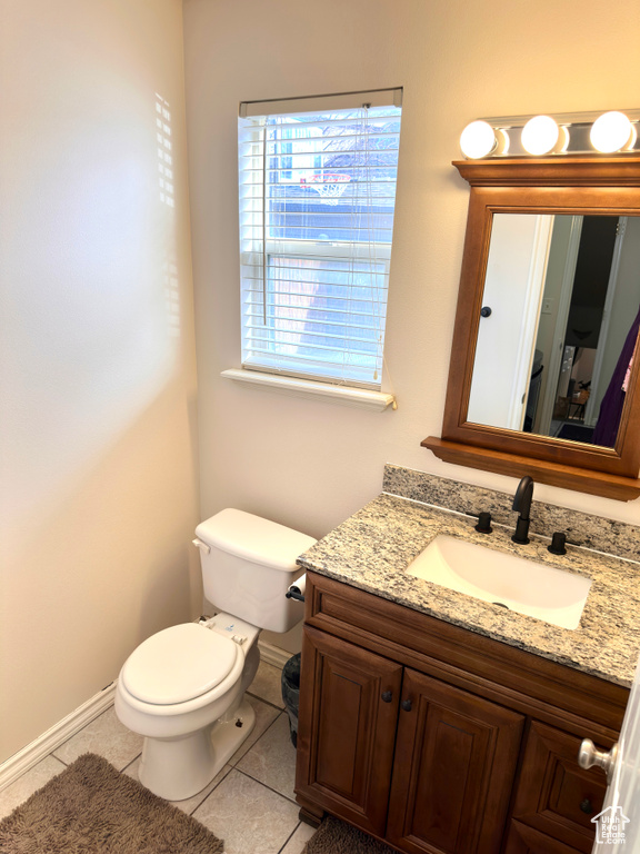 Half bath with tile patterned floors, toilet, vanity, and baseboards