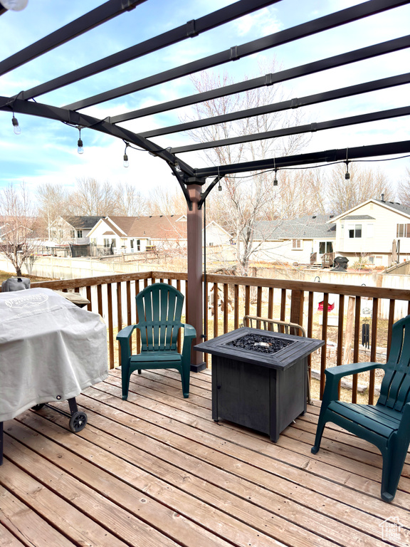 Wooden deck with a pergola, a fire pit, a residential view, and grilling area