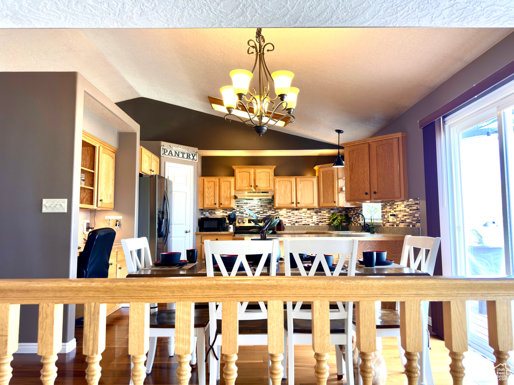 Dining space featuring vaulted ceiling, a notable chandelier, and a textured ceiling