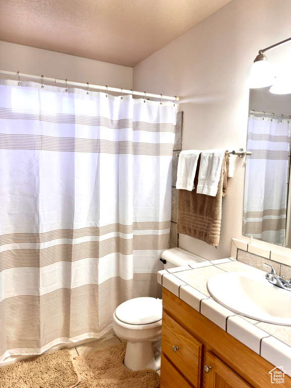 Full bathroom featuring vanity, a shower with shower curtain, toilet, and a textured ceiling