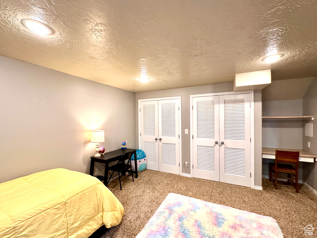 Carpeted bedroom featuring french doors, multiple closets, a textured ceiling, and baseboards