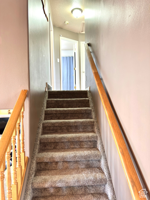 Stairway featuring a textured ceiling