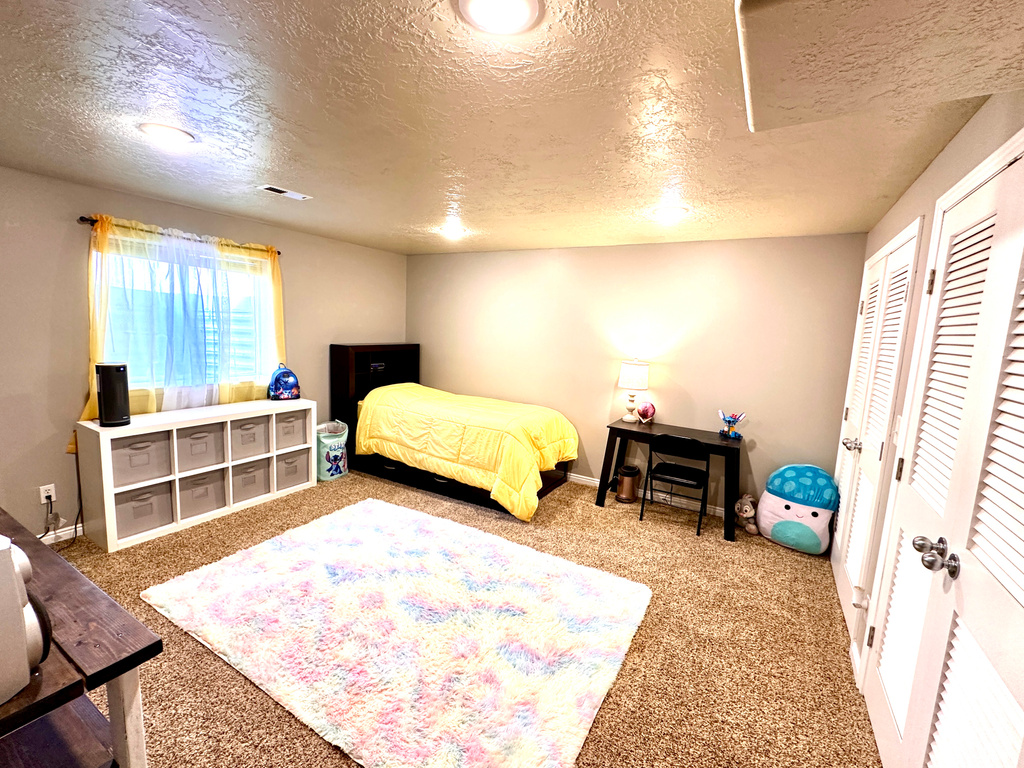 Carpeted bedroom featuring baseboards, visible vents, two closets, and a textured ceiling