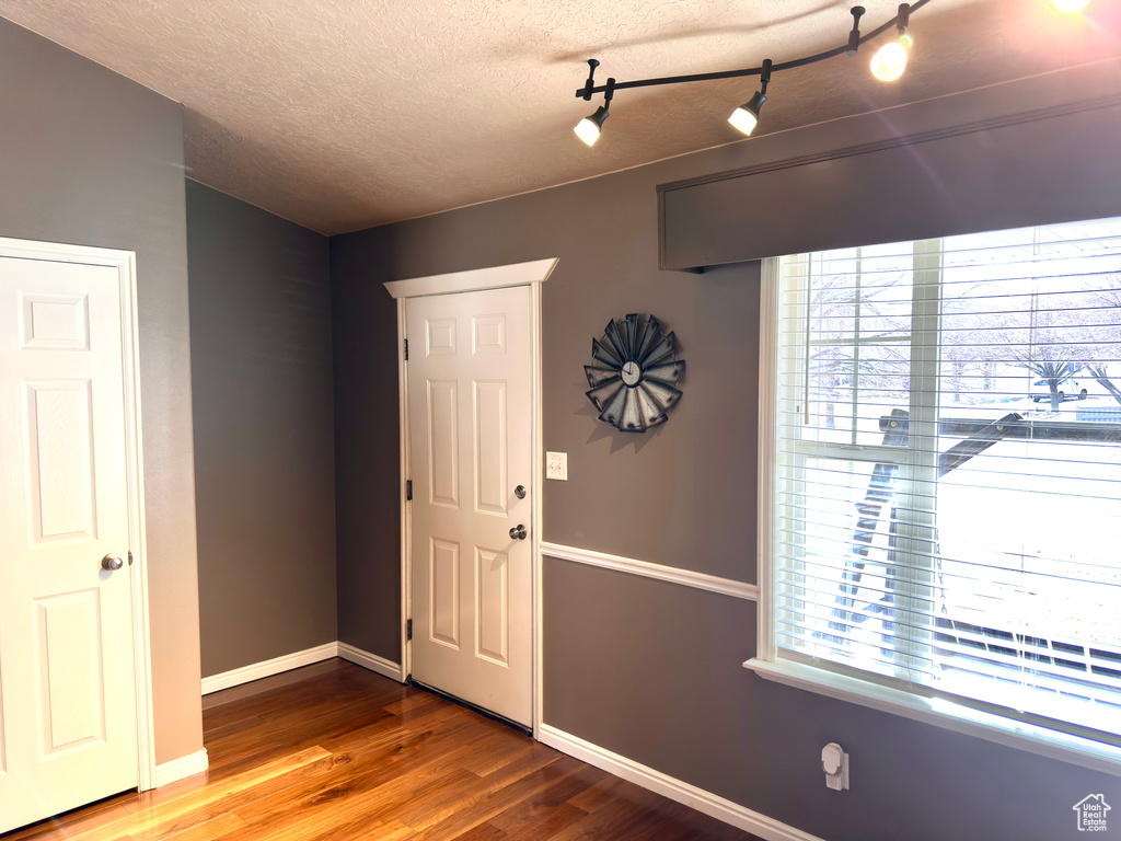 Entrance foyer with a textured ceiling, baseboards, and wood finished floors