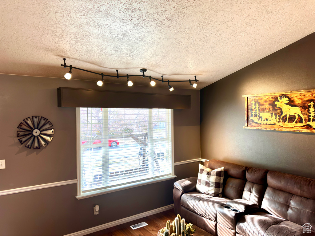 Living area with dark wood finished floors, baseboards, visible vents, and a textured ceiling