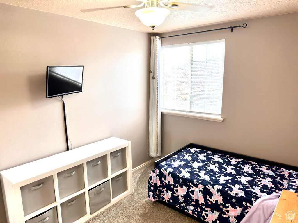 Bedroom featuring a textured ceiling, ceiling fan, and carpet flooring