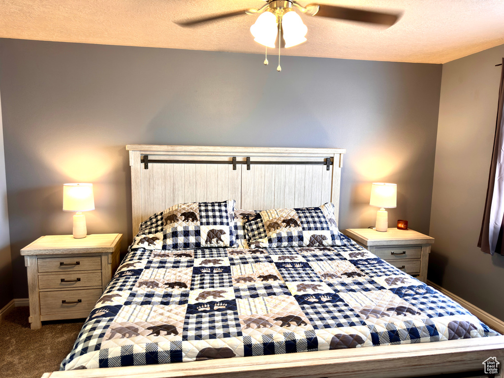 Carpeted bedroom with a textured ceiling, a ceiling fan, and baseboards