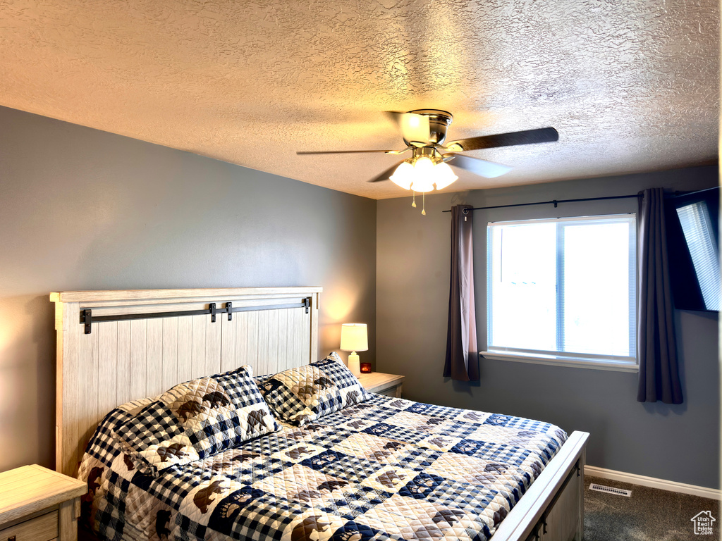 Bedroom with visible vents, ceiling fan, baseboards, carpet, and a textured ceiling