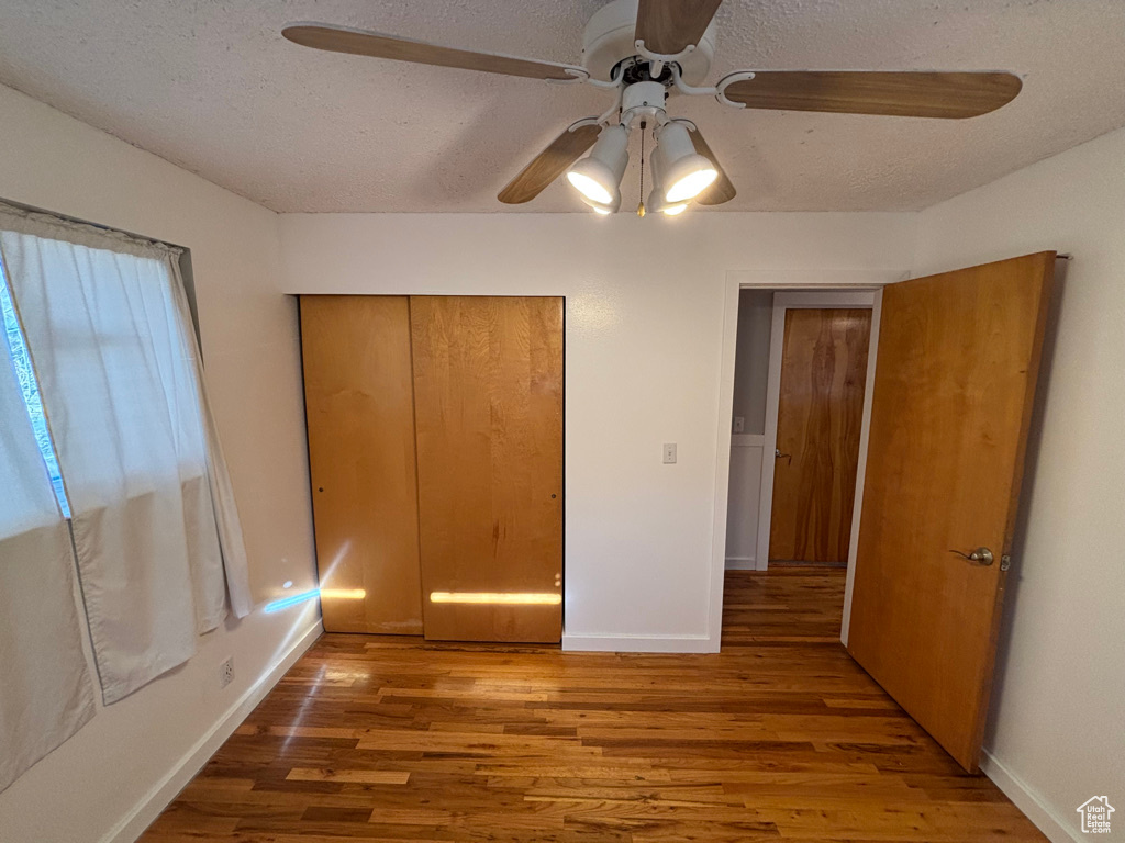 Unfurnished bedroom featuring a textured ceiling, a ceiling fan, baseboards, and wood finished floors