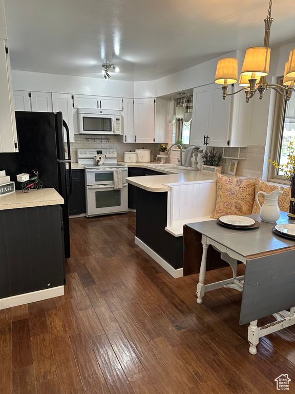 Kitchen featuring white appliances, light countertops, a peninsula, backsplash, and dark wood-type flooring