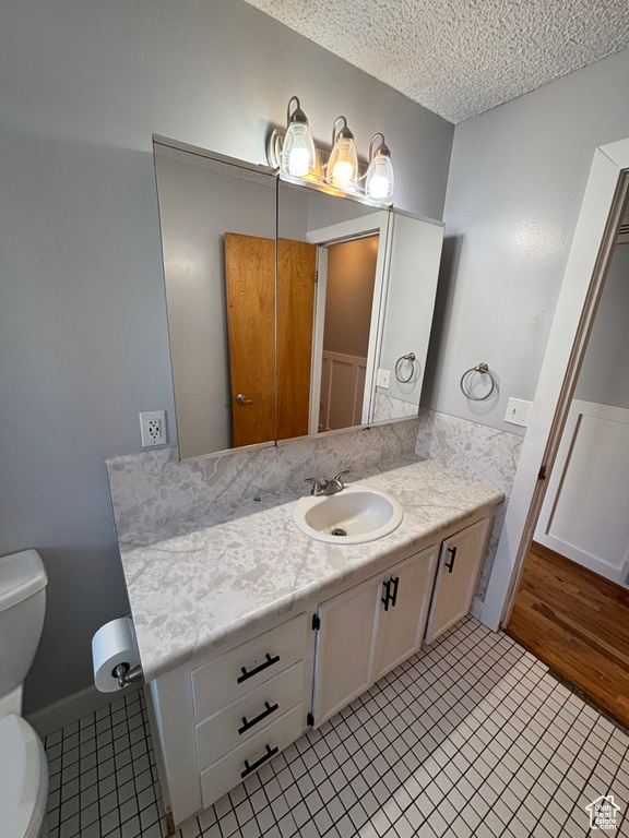 Bathroom featuring vanity, a textured ceiling, tile patterned flooring, and toilet