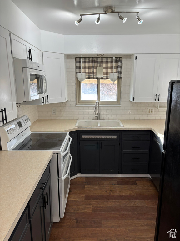 Kitchen with white electric stove, dark wood-style flooring, freestanding refrigerator, a sink, and white cabinetry