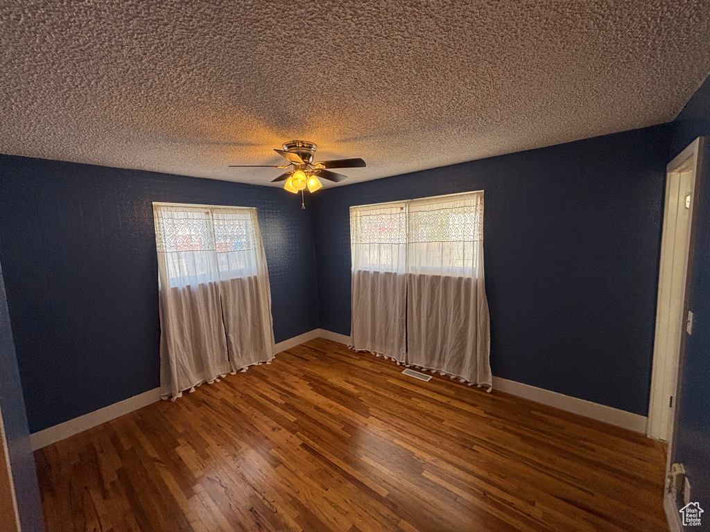 Empty room featuring visible vents, baseboards, and wood finished floors
