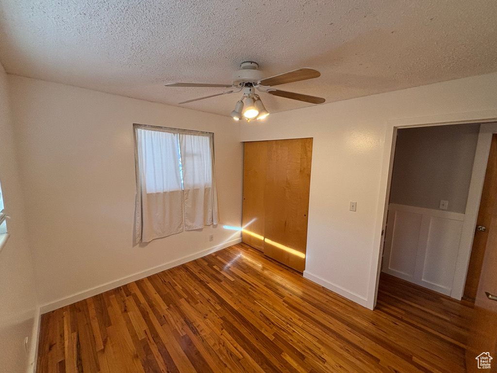 Unfurnished bedroom with a closet, a textured ceiling, a ceiling fan, and wood finished floors