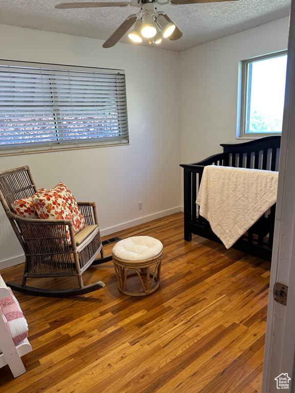 Bedroom with wood finished floors, a textured ceiling, baseboards, and ceiling fan