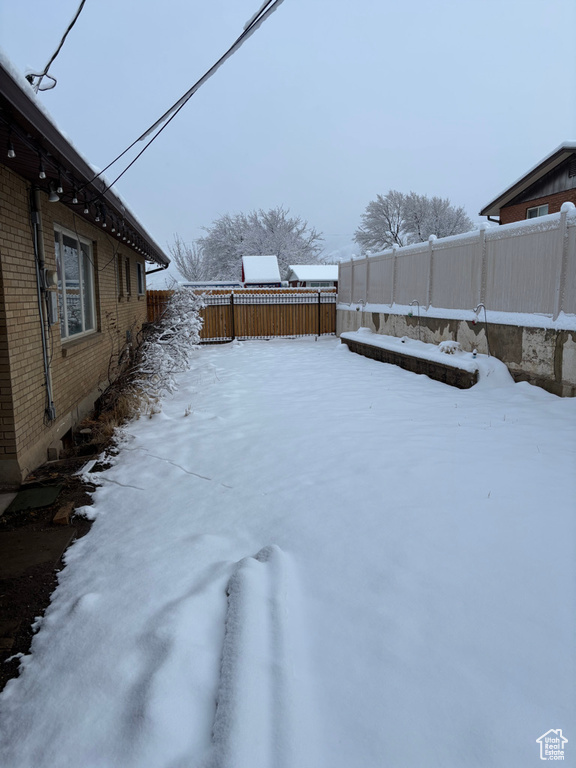 Yard covered in snow featuring a fenced backyard