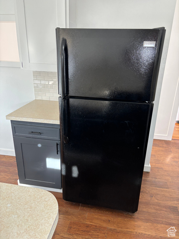 Room details with baseboards, dark wood finished floors, light countertops, decorative backsplash, and freestanding refrigerator