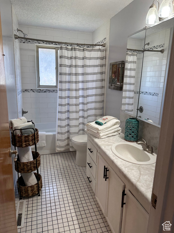 Bathroom featuring a textured ceiling, vanity, shower / tub combo with curtain, toilet, and tile patterned floors