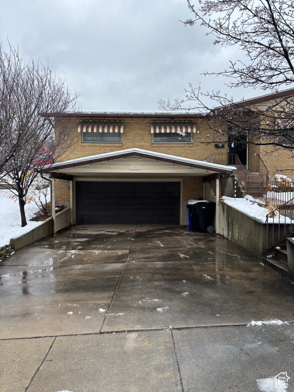 View of side of property featuring brick siding, driveway, and a garage