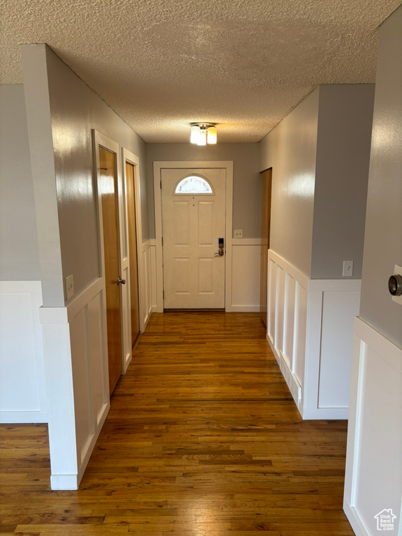 Entryway with dark wood-type flooring, a wainscoted wall, and a textured ceiling