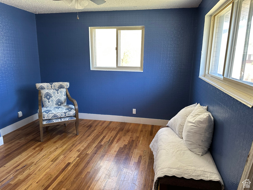Sitting room featuring hardwood / wood-style flooring, a ceiling fan, and baseboards